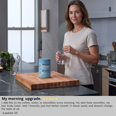 Woman in a kitchen holding a glass of water next to a container of collagen powder.